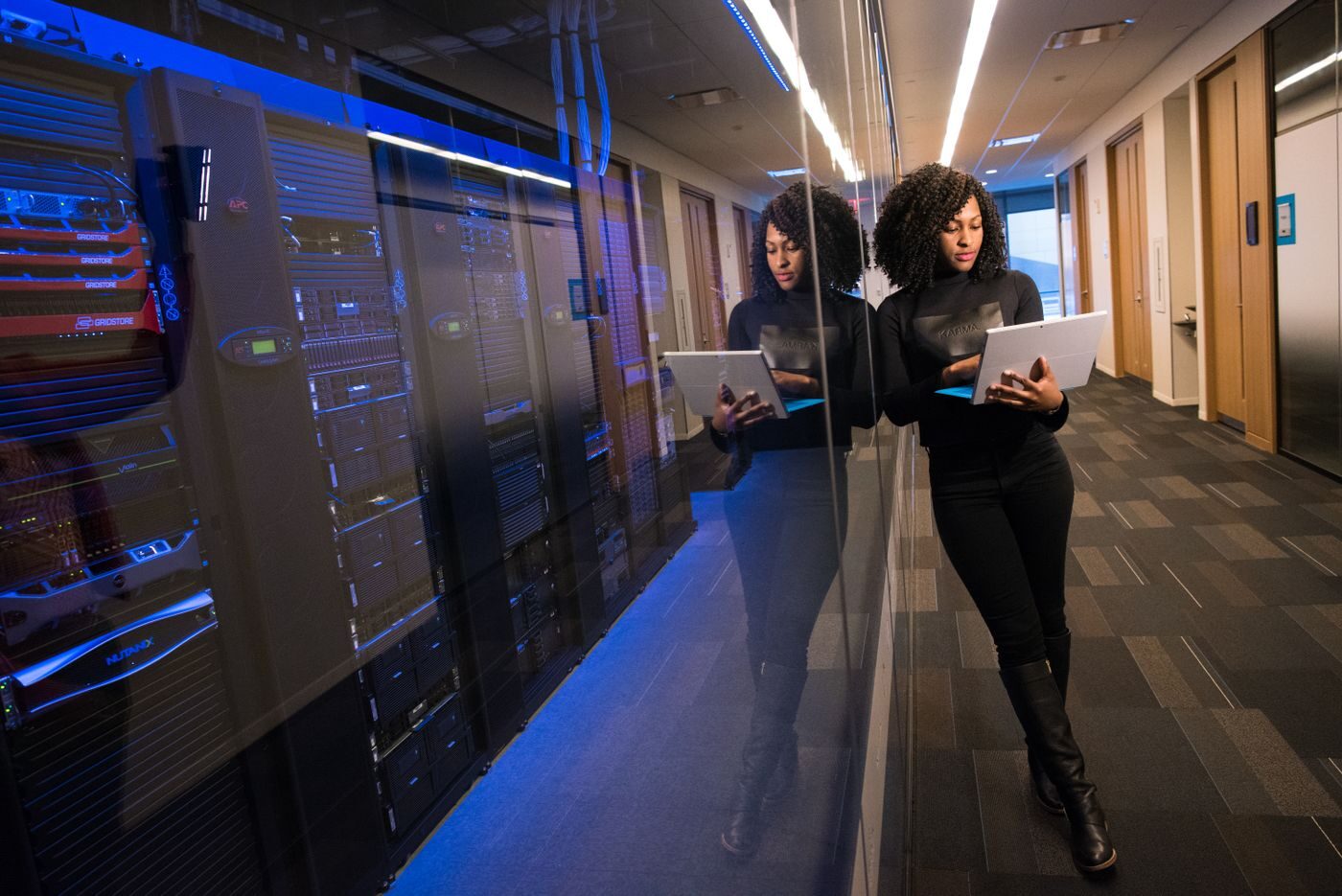 Duas profissionais com tablets em corredor de data center